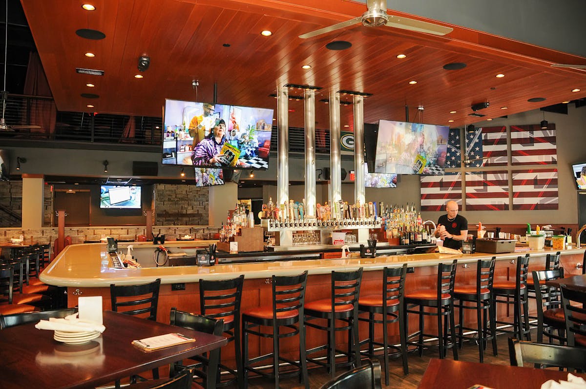 The bar at Blackfinn Ameripub Ballantyne, taps lit, screens above the shelves.